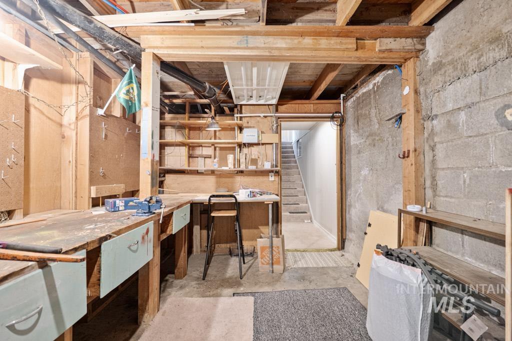 259 Highway 12 Pomeroy, WA 99347 - Photo 30 of 45 Unfinished basement space featuring exposed wood framing, concrete block walls, and built-in wooden workbenches with integrated shelving