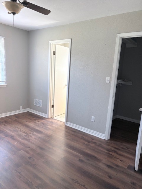 1917 Castle Gate Circle San Marcos, TX 78666 - Photo 16 of 21 Unfurnished bedroom featuring a walk in closet, dark wood-style flooring, and a ceiling fan