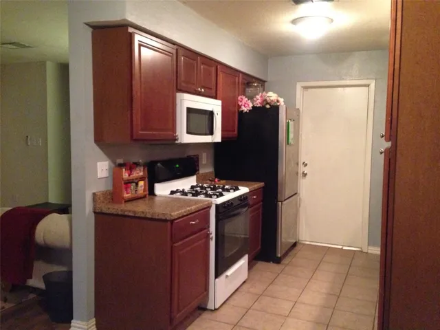 a kitchen with stainless steel appliances granite countertop a stove top oven a refrigerator and a microwave