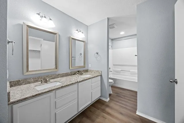 a bathroom with a granite countertop double vanity sink a mirror and a shower