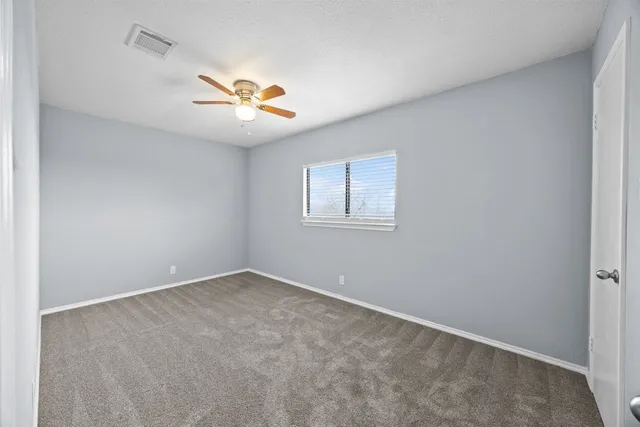 an empty room with a window and a fan