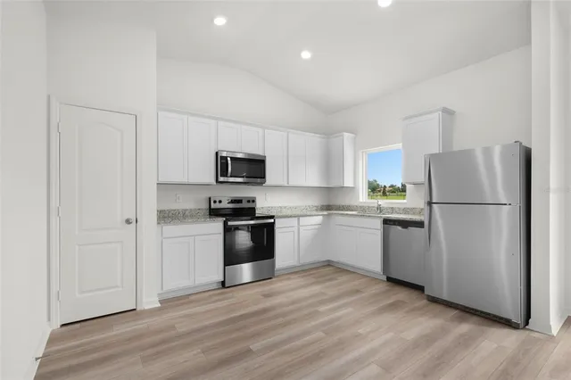 a kitchen with a refrigerator stove and white cabinets