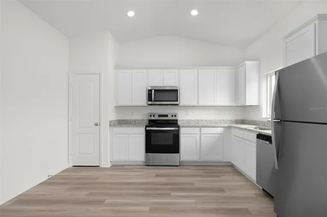 a kitchen with a refrigerator stove and white cabinets