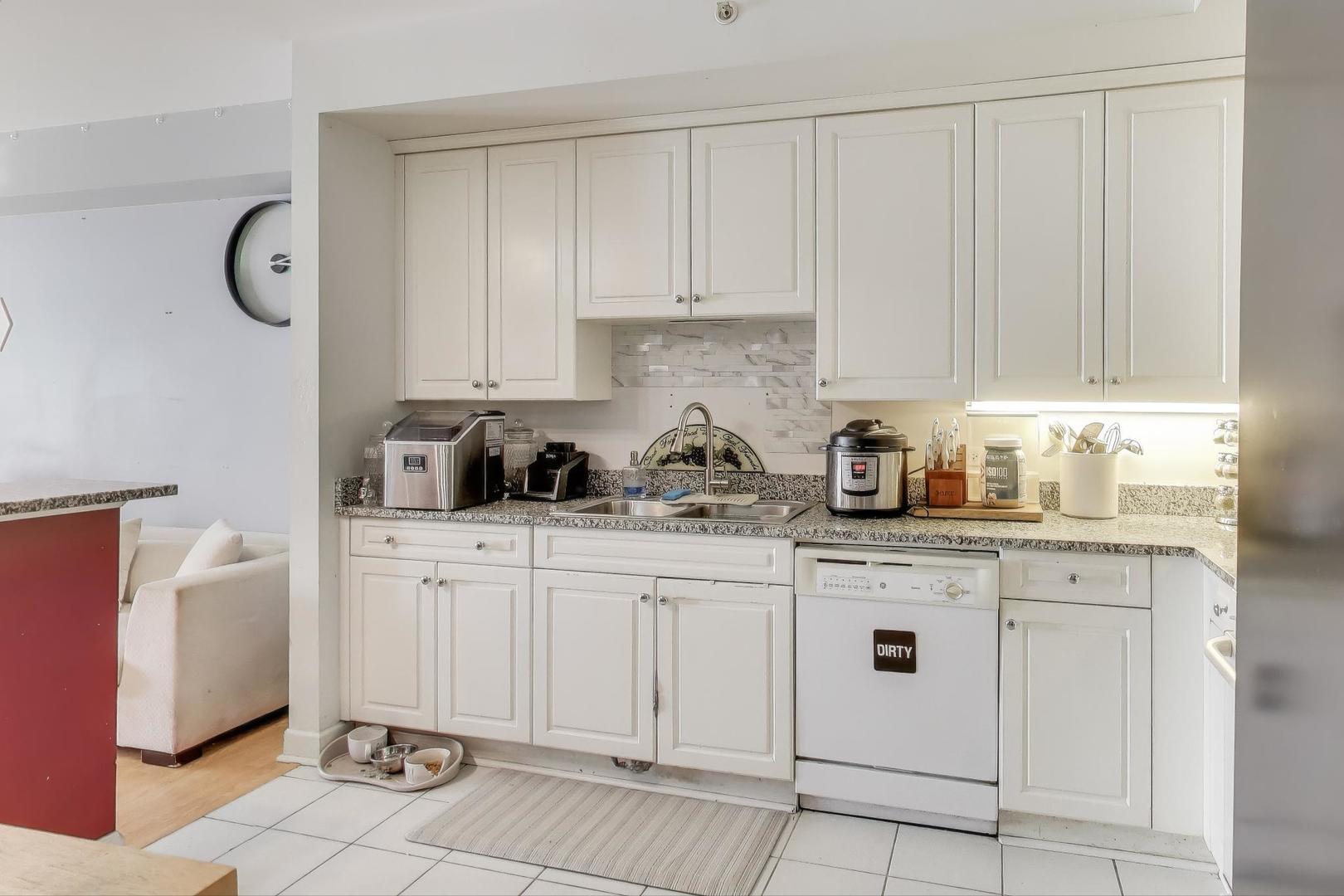 8300 Callie Avenue, Unit 310 Morton Grove, IL 60053 - Photo 12 of 25 a kitchen with granite countertop white cabinets and stainless steel appliances