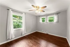 a view of an empty room with wooden floor and a window