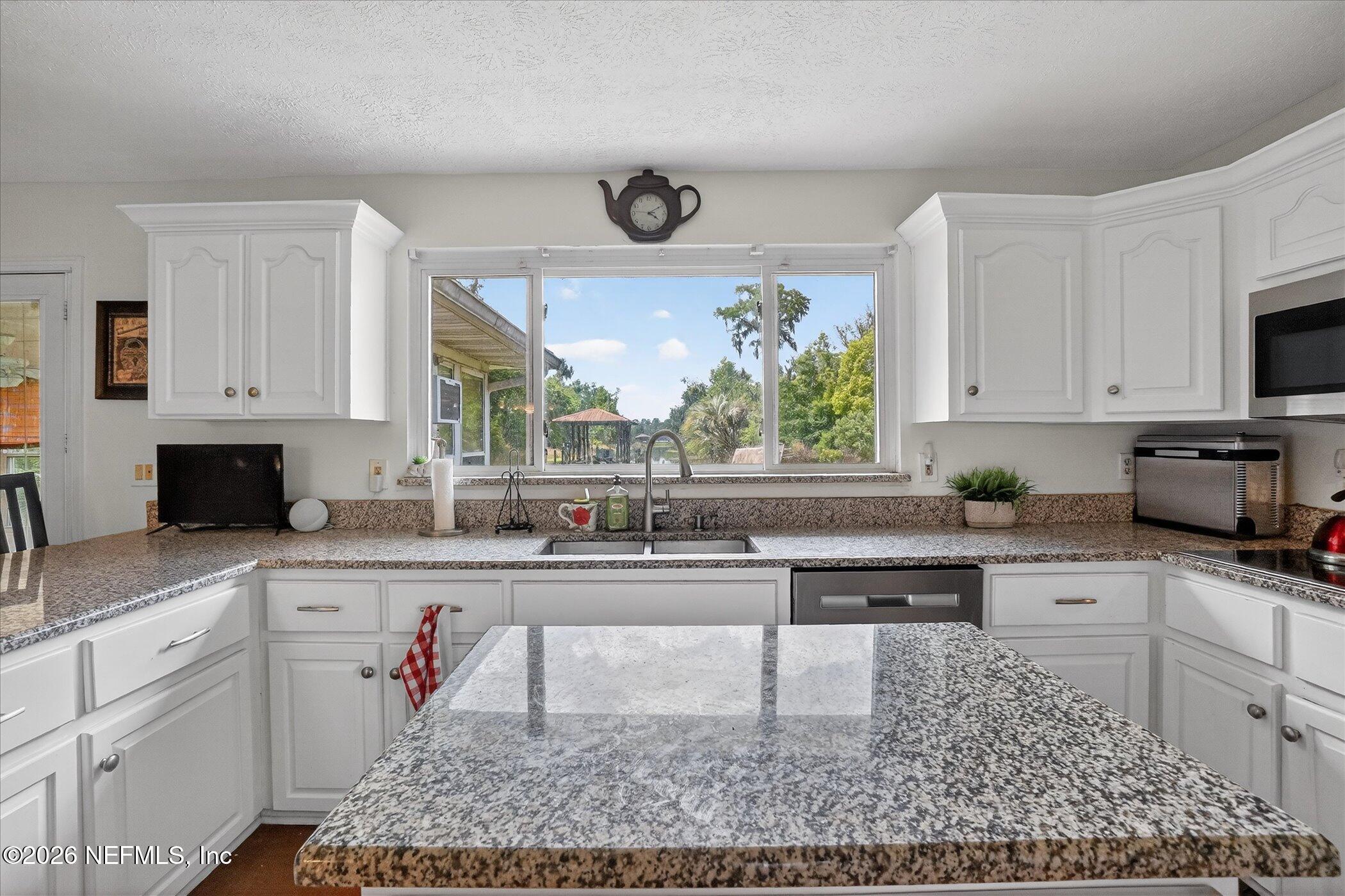 4242 Hillwood Road Jacksonville, FL 32223 - Photo 26 of 36 a kitchen with a stove a sink and cabinets