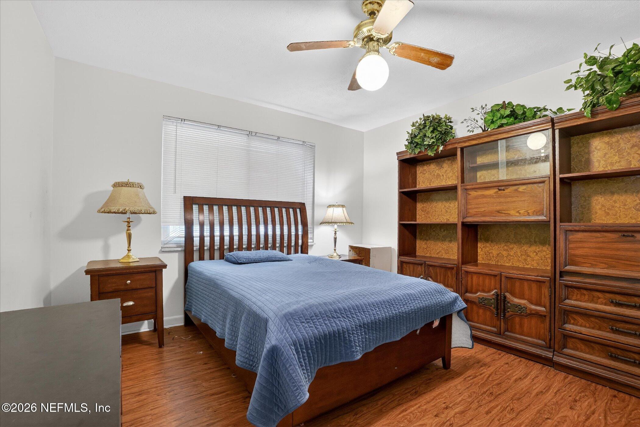4242 Hillwood Road Jacksonville, FL 32223 - Photo 32 of 36 a bedroom with a bed a chandelier and potted plant on the wooden floor