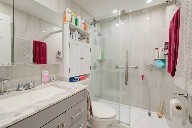 a bathroom with a sink vanity granite toilet and shower