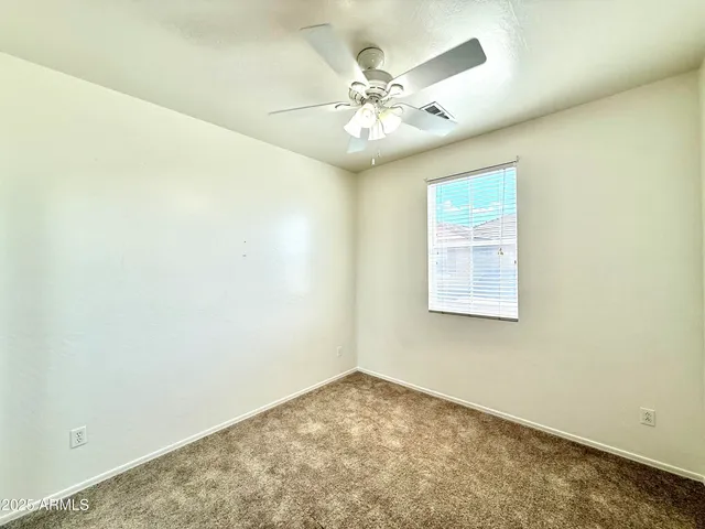 an empty room with a chandelier fan and windows