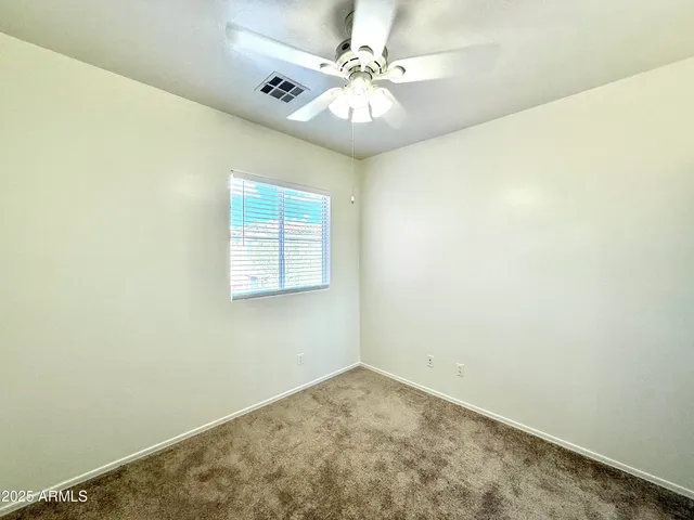 an empty room with a chandelier fan and windows