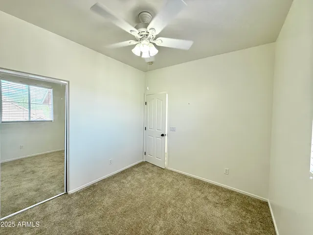 an empty room with a chandelier fan and windows