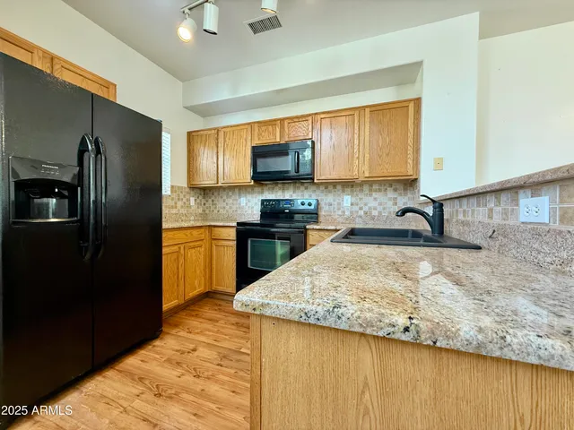 a kitchen with granite countertop a refrigerator and a stove top oven