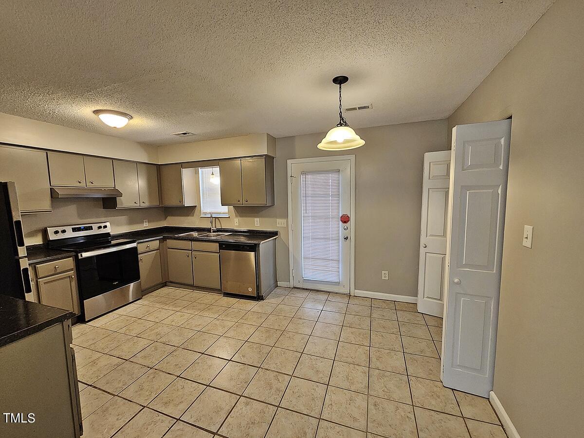 11 Howlett Place Durham, NC 27703 - Photo 11 of 27 a kitchen with granite countertop a stove cabinets and refrigerator
