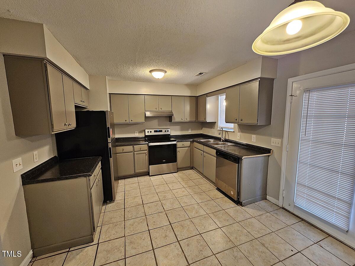 11 Howlett Place Durham, NC 27703 - Photo 12 of 27 a kitchen with granite countertop a sink cabinets and stainless steel appliances