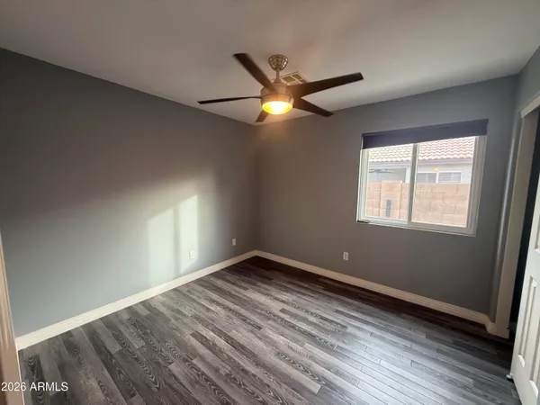 a view of empty room with wooden floor and fan