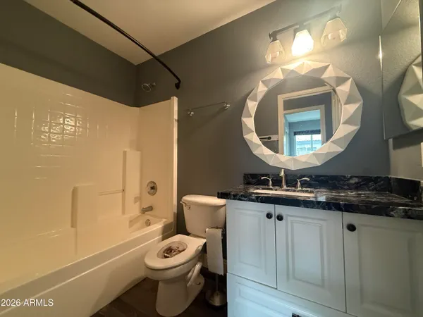 a bathroom with a toilet sink vanity granite and a mirror