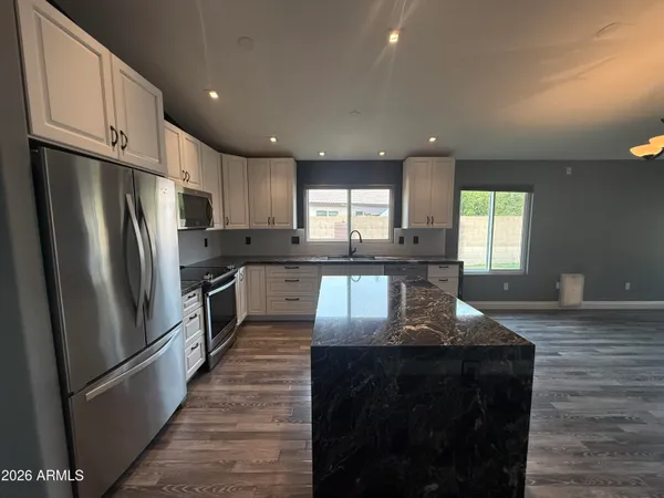 a kitchen with granite countertop a refrigerator a sink a stove and cabinets