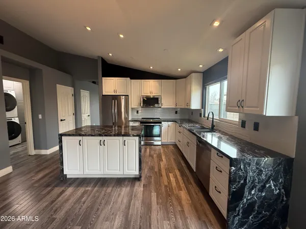 a large kitchen with stainless steel appliances kitchen island granite countertop wooden cabinets and a granite counter tops