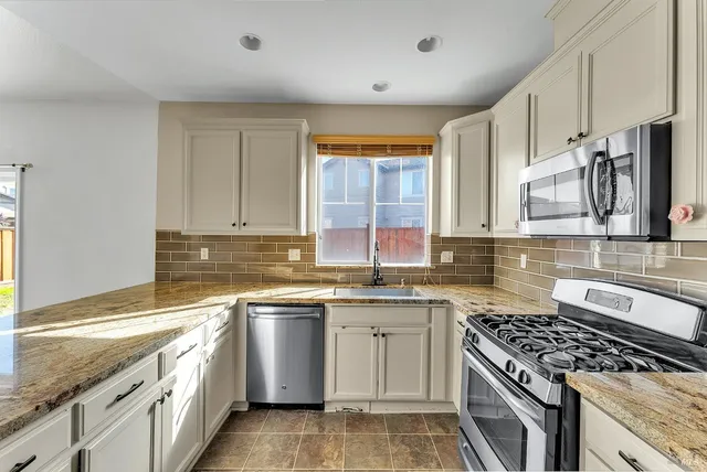 a kitchen with stainless steel appliances granite countertop a sink stove cabinets and granite counter top