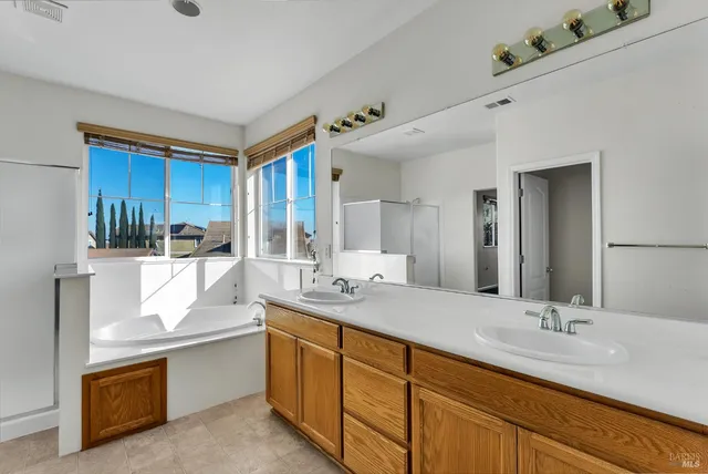a bathroom with double vanity sinks double vanity tub shower and a mirror