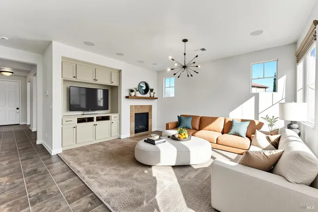 a living room with furniture a flat screen tv and a chandelier