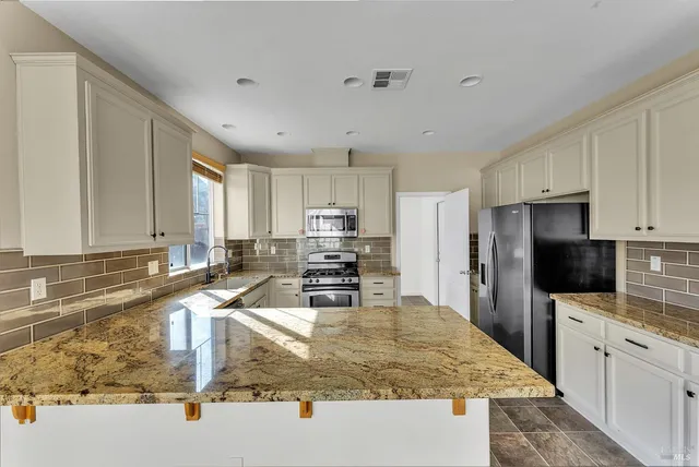 a kitchen with stainless steel appliances granite countertop a sink stove and refrigerator