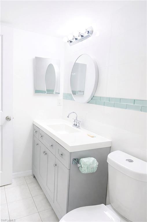 3325 Airport Road North, Unit F1 Naples, FL 34105 - Photo 5 of 7 Half bath with vanity, tile walls, and light tile patterned floors