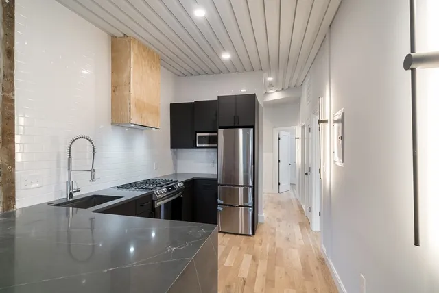 a kitchen with stainless steel appliances a refrigerator sink and wooden cabinets
