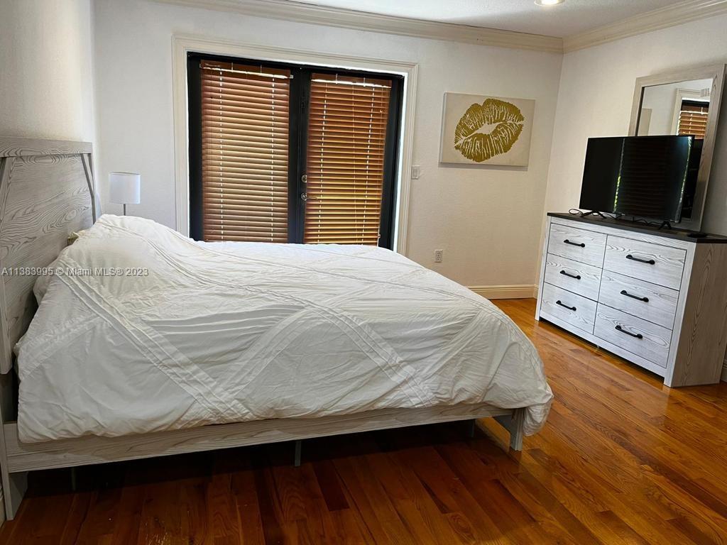 1411 Normandy Drive Miami Beach, FL 33141 - Photo 11 of 23 a bedroom with a bed and a flat tv screen on dresser