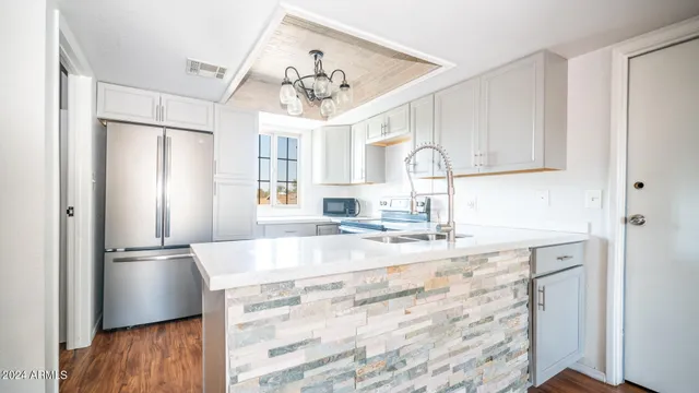 a view of a kitchen with kitchen island a sink stainless steel appliances and cabinets