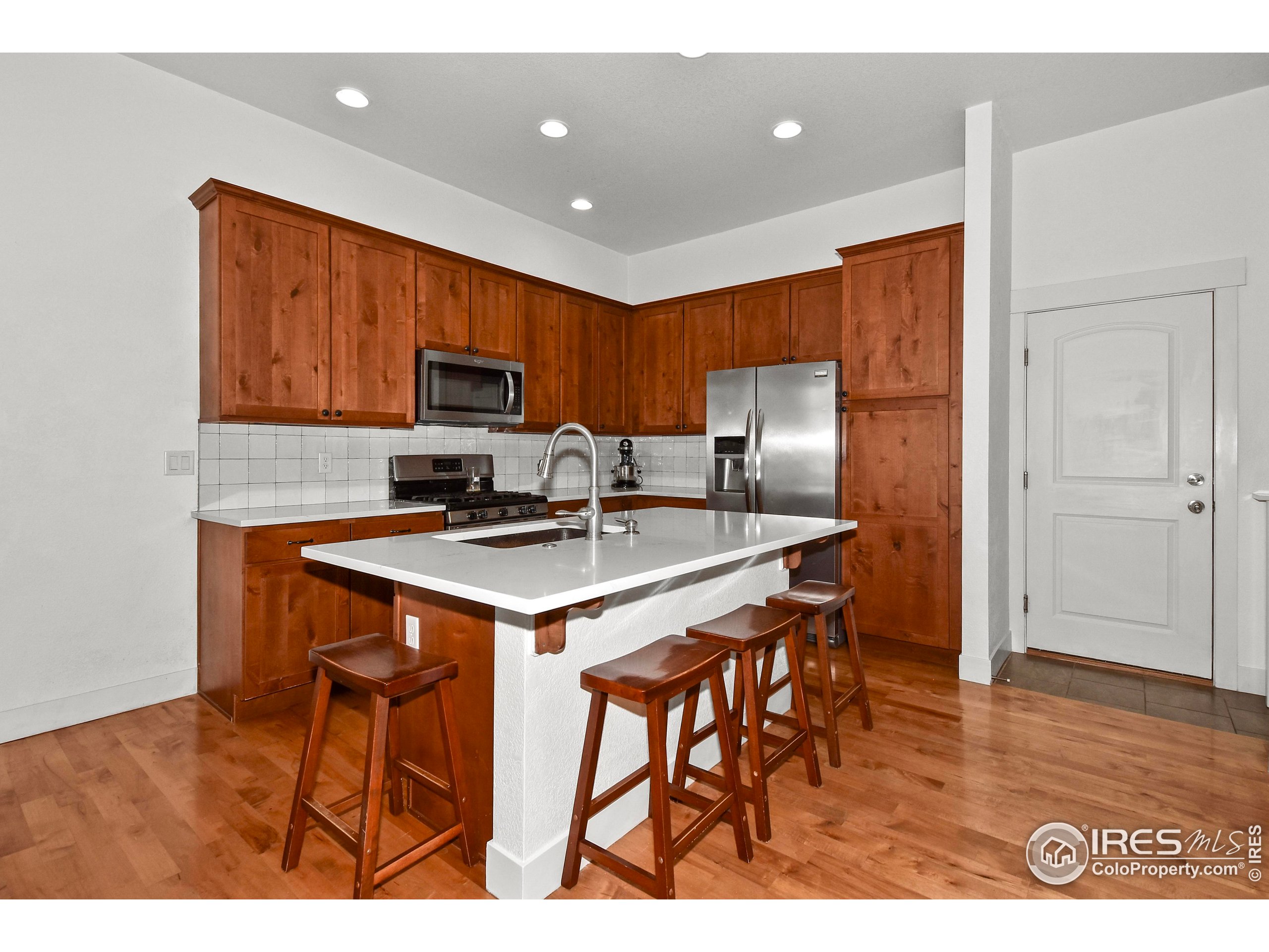 2172 Cape Hatteras Drive, Unit 2 Windsor, CO 80550 - Photo 16 of 46 a kitchen with stainless steel appliances a stove a refrigerator a sink a microwave a refrigerator and white cabinets with wooden floor