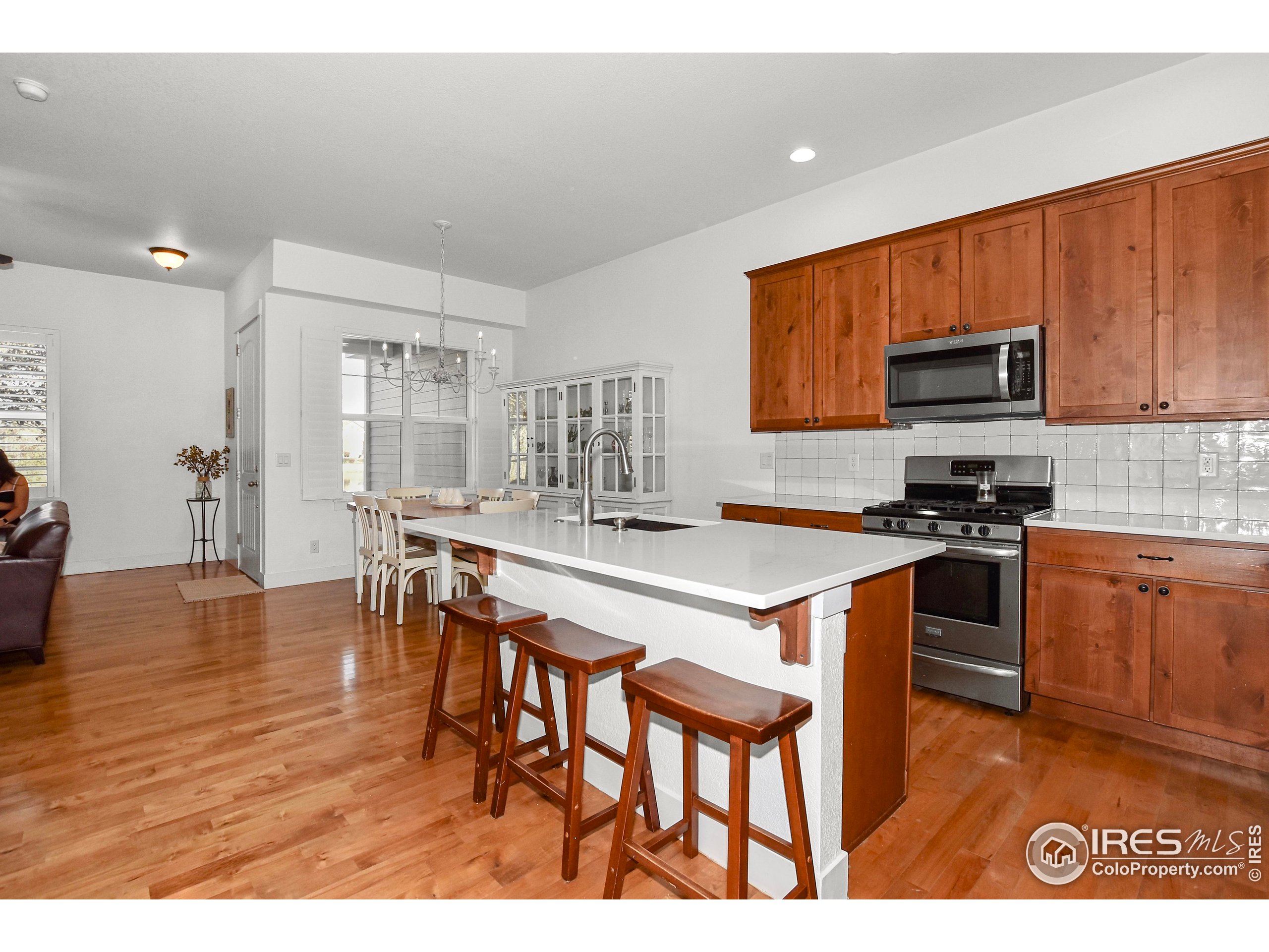 2172 Cape Hatteras Drive, Unit 2 Windsor, CO 80550 - Photo 17 of 46 a kitchen with stainless steel appliances a stove a sink a microwave a dining table and chairs