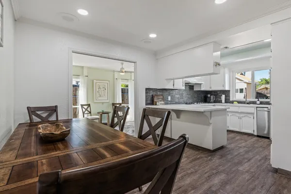 a kitchen with a dining table chairs and white appliances