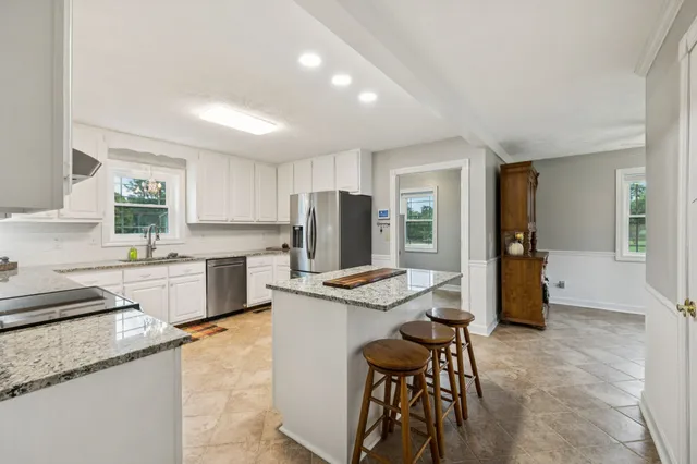 a kitchen with granite countertop white cabinets and stainless steel appliances
