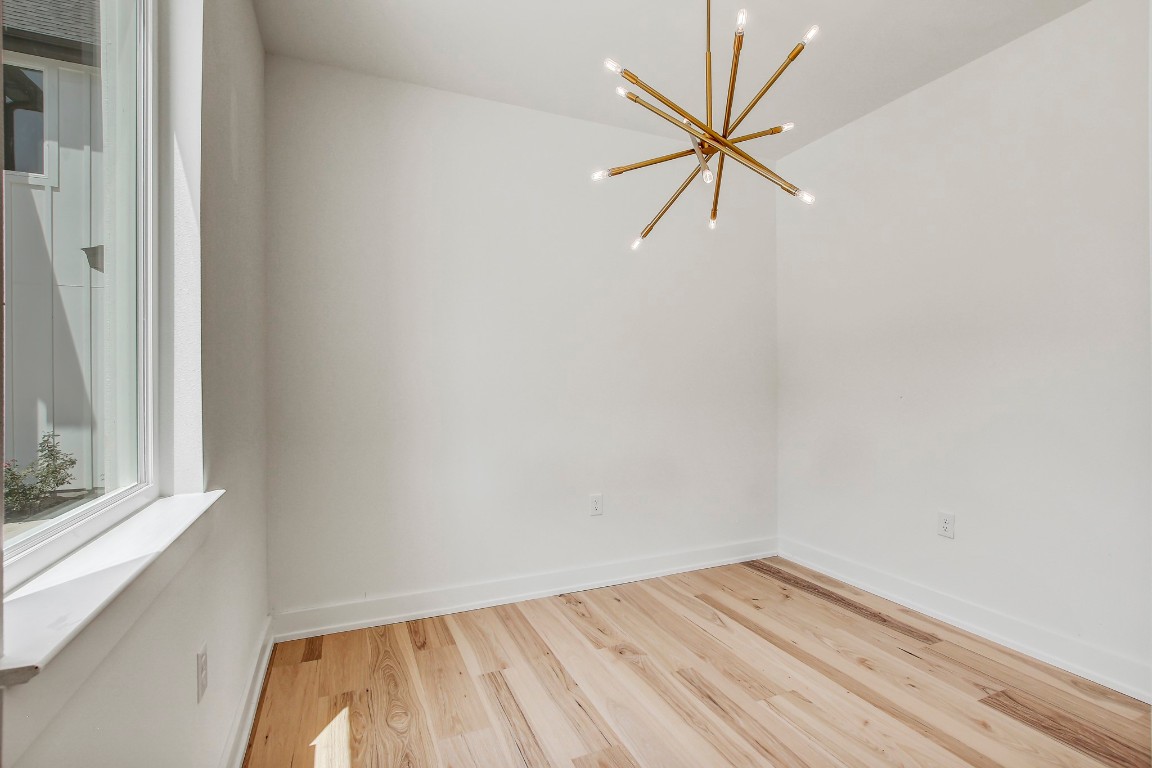 4127 East 12th Street, Unit 4 Austin, TX 78721 - Photo 11 of 32 Unfurnished room featuring a chandelier, wood finished floors, and baseboards