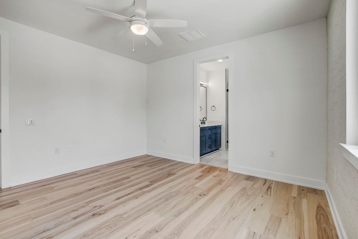 4127 East 12th Street, Unit 4 Austin, TX 78721 - Photo 15 of 32 Empty room featuring a ceiling fan, light wood finished floors, and baseboards