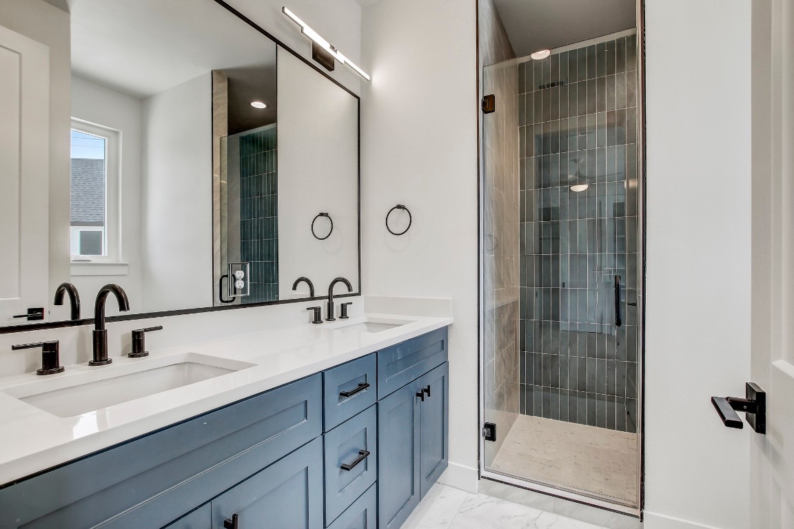 4127 East 12th Street, Unit 4 Austin, TX 78721 - Photo 17 of 32 Bathroom with double vanity, marble finish flooring, a stall shower, and baseboards