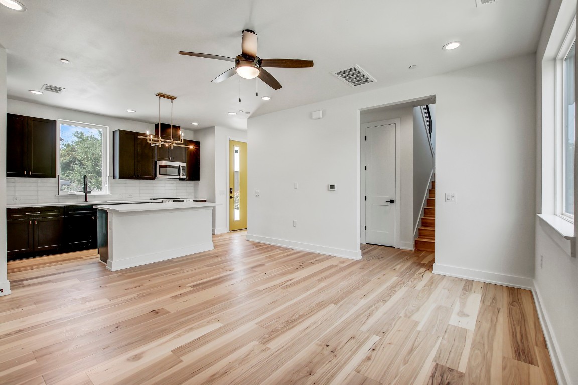 4127 East 12th Street, Unit 4 Austin, TX 78721 - Photo 2 of 32 Kitchen with stainless steel microwave, backsplash, ceiling fan, light countertops, and light wood finished floors