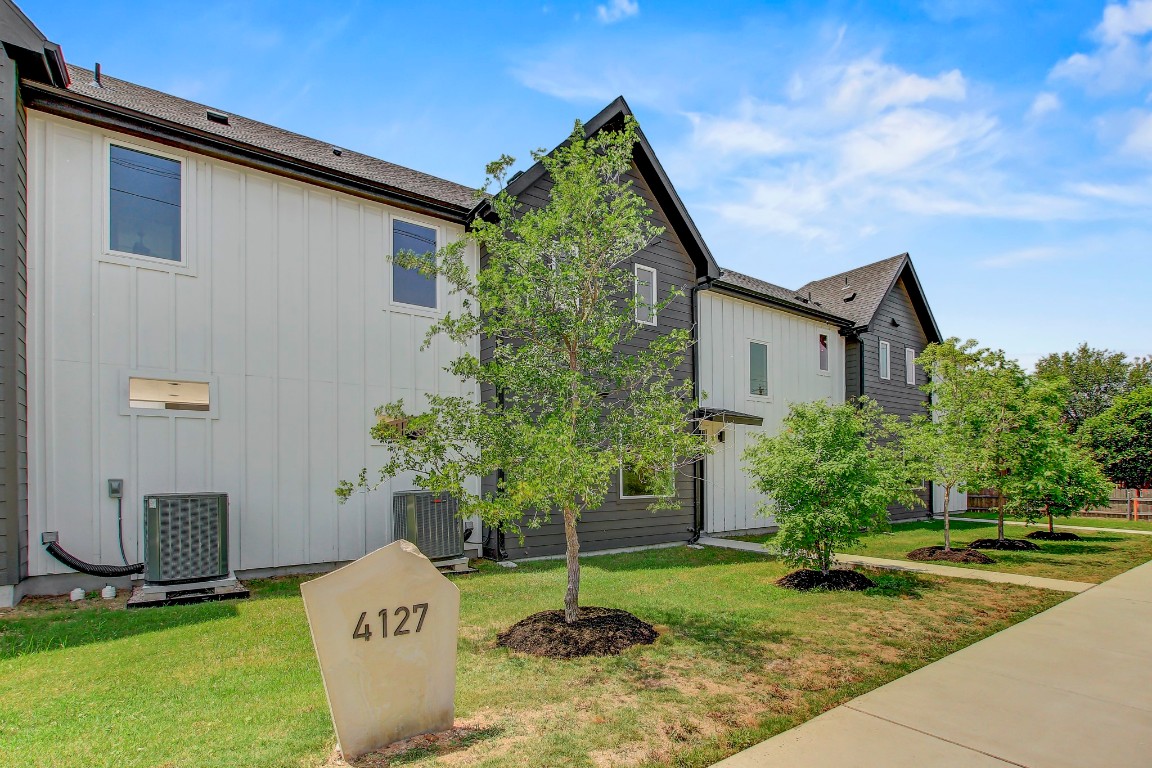 4127 East 12th Street, Unit 4 Austin, TX 78721 - Photo 32 of 32 View of side of property featuring board and batten siding, cooling unit, and a lawn