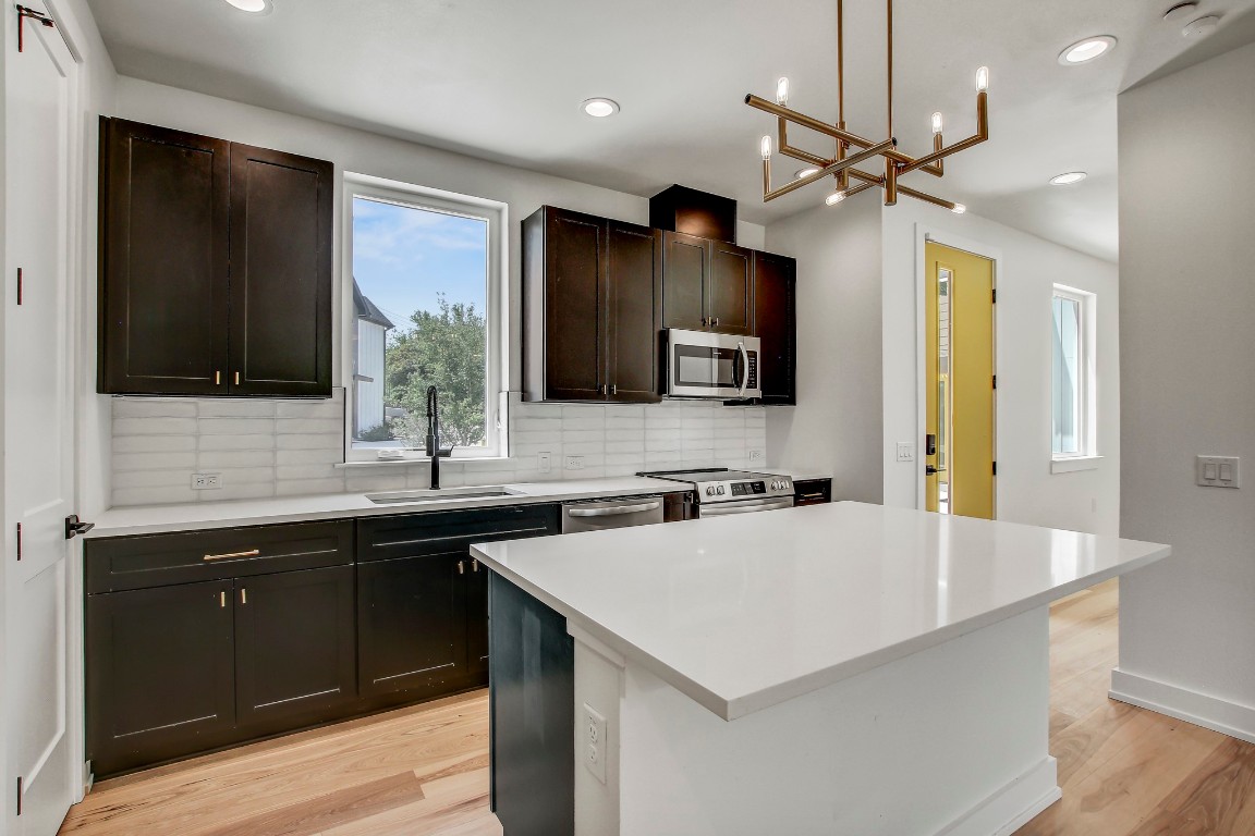4127 East 12th Street, Unit 4 Austin, TX 78721 - Photo 5 of 32 Kitchen with appliances with stainless steel finishes, a sink, tasteful backsplash, light wood-type flooring, and recessed lighting
