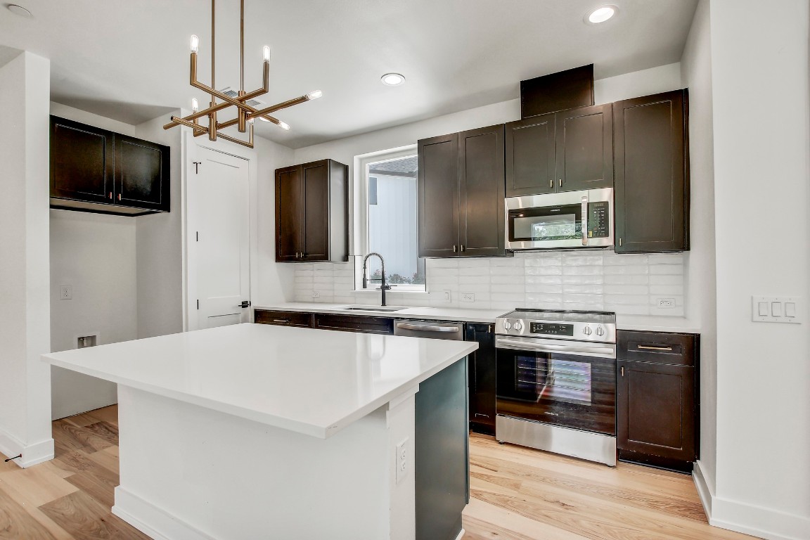 4127 East 12th Street, Unit 4 Austin, TX 78721 - Photo 6 of 32 Kitchen with stainless steel appliances, a sink, light wood-style floors, a chandelier, and recessed lighting