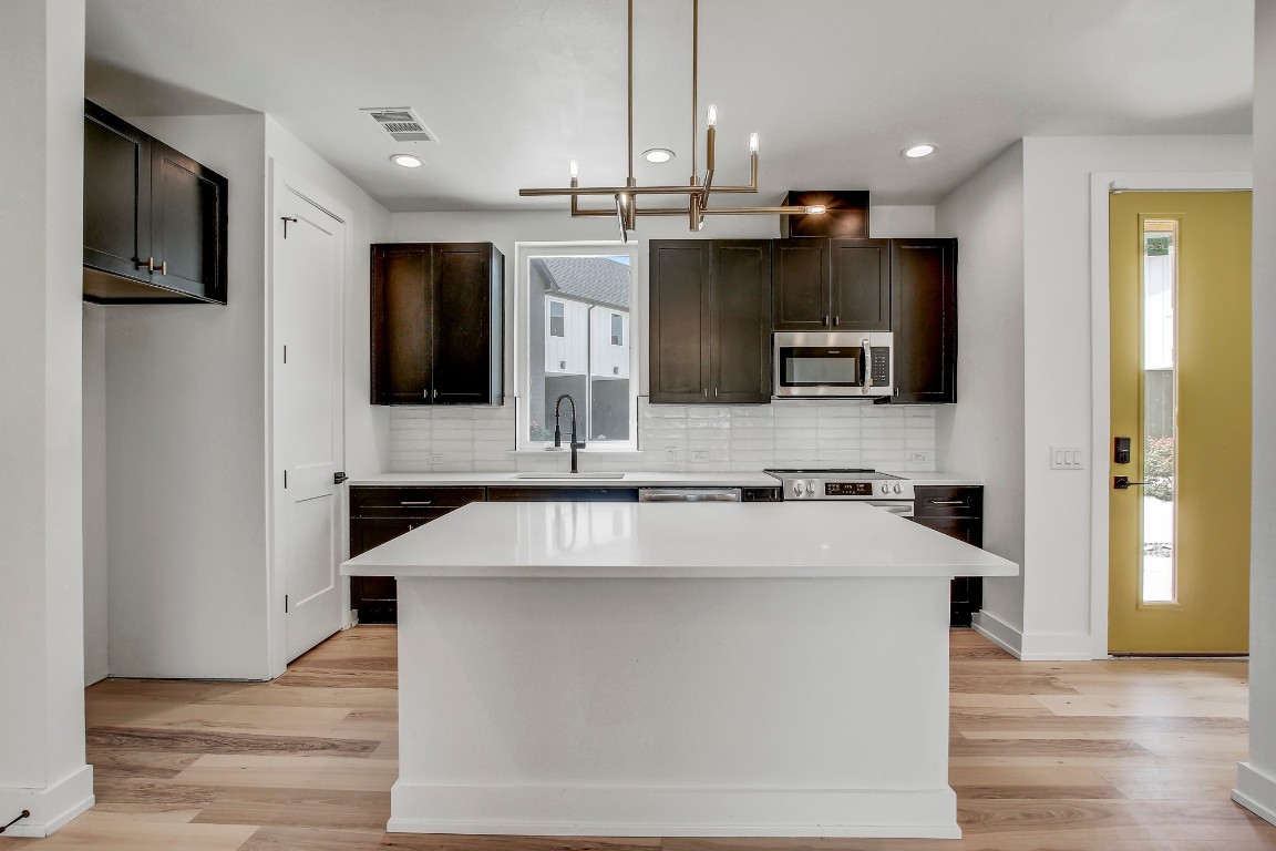 4127 East 12th Street, Unit 4 Austin, TX 78721 - Photo 7 of 32 Kitchen featuring stainless steel appliances, a sink, light wood-style flooring, healthy amount of natural light, and recessed lighting