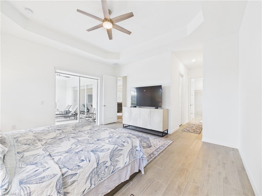 5412 Fancourt Links Way Ave Maria, FL 34142 - Photo 16 of 39 Bedroom with a raised ceiling, light wood-style floors, a ceiling fan, and ensuite bathroom
