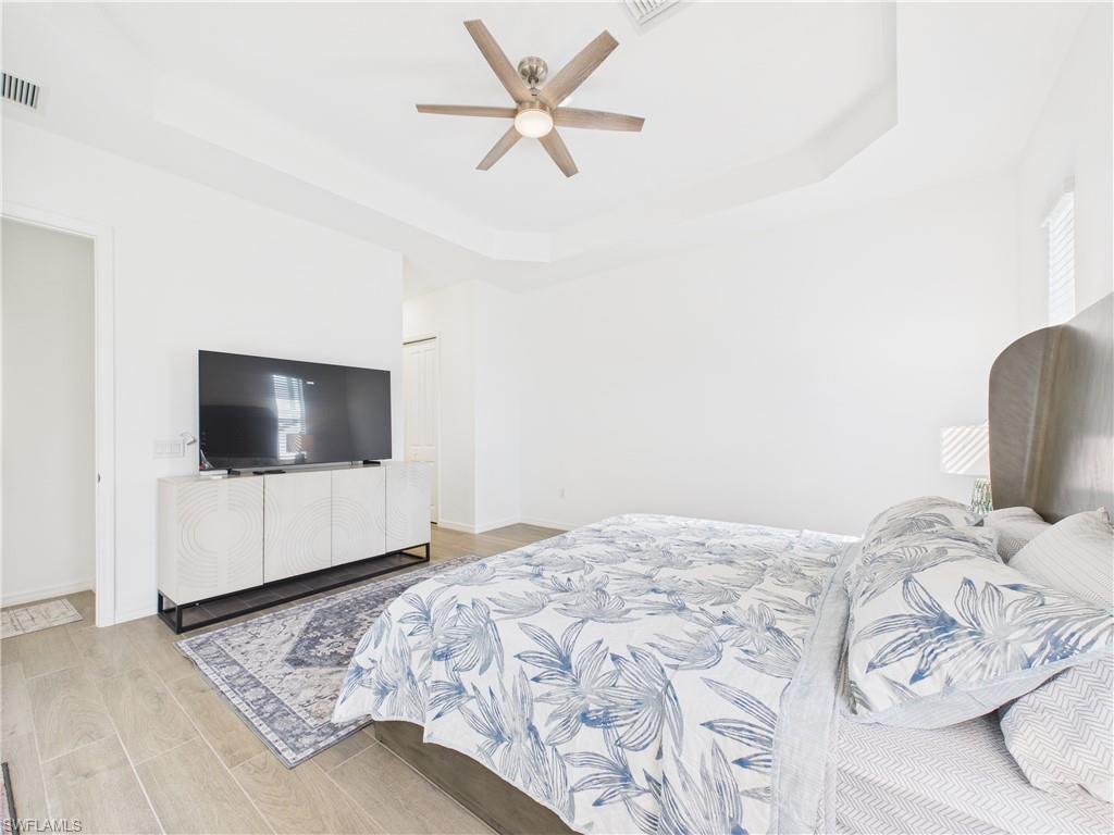 5412 Fancourt Links Way Ave Maria, FL 34142 - Photo 22 of 39 Bedroom with a tray ceiling, light wood-type flooring, and a ceiling fan