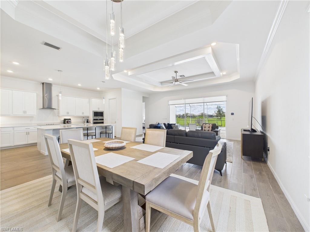 5412 Fancourt Links Way Ave Maria, FL 34142 - Photo 10 of 39 Dining space featuring a tray ceiling, light wood-style floors, a ceiling fan, ornamental molding, and recessed lighting