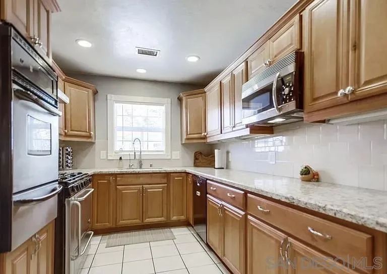 1663 Buckeye Drive El Cajon, CA 92021 - Photo 8 of 20 a kitchen with stainless steel appliances granite countertop a sink stove and refrigerator