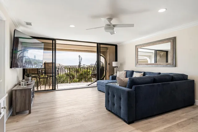 a living room with furniture ceiling fan and a large window