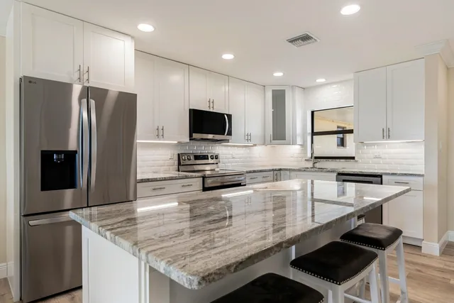 a kitchen with stainless steel appliances granite countertop a sink stove and microwave