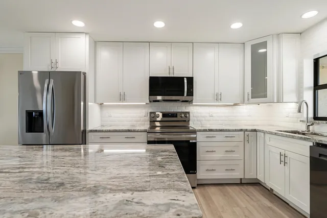 a kitchen with stainless steel appliances kitchen island granite countertop a stove top oven a sink a dining table and chairs