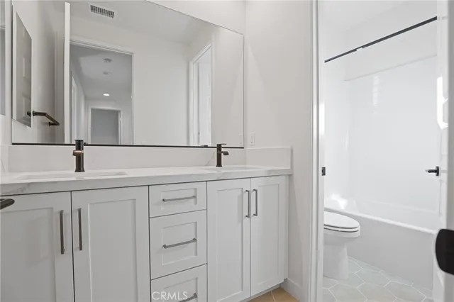 a bathroom with a double vanity sink toilet and a mirror